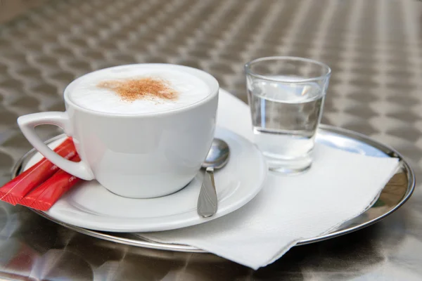 Xícara de cappuccino e um copo de água — Fotografia de Stock