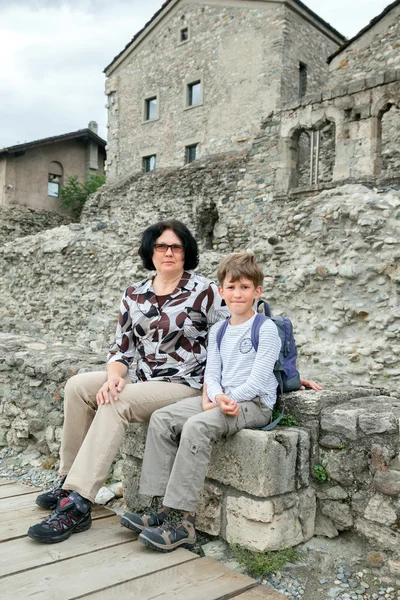 Žena a chlapec sedí na starých bloků — Stock fotografie