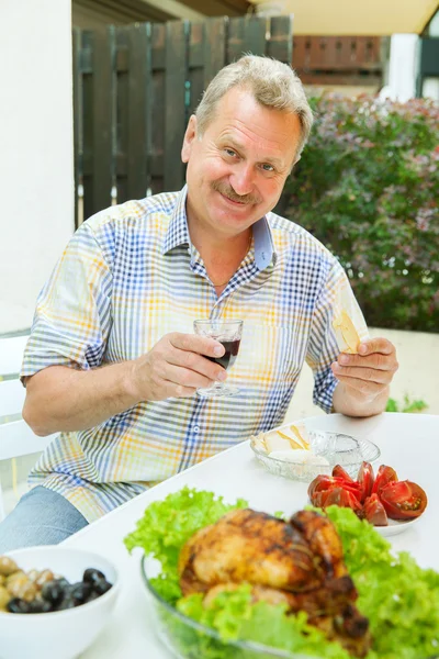 Elderly man has lunch on the patio — Stock Photo, Image