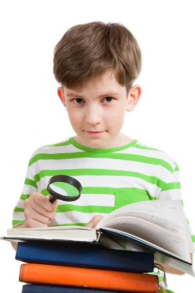 Schoolboy with magnifying glass and books — Stock Photo, Image