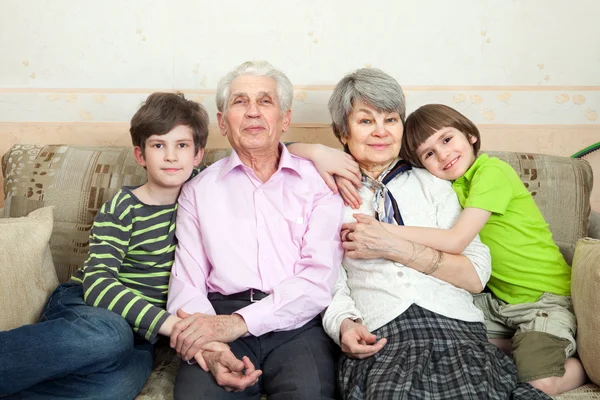 Grandfather, grandmother and grandchildren on sofa — Stock Photo, Image