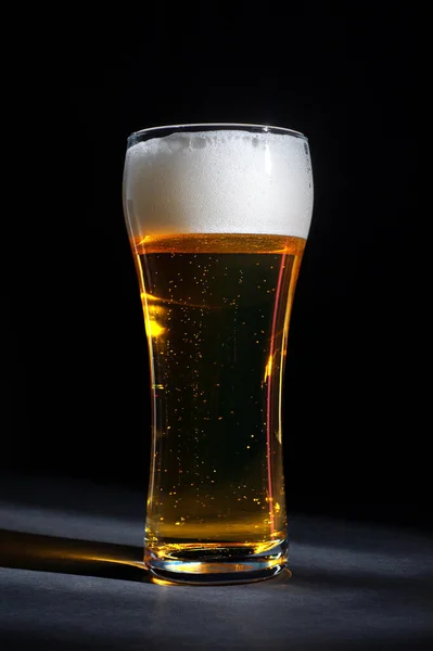 Frisches Bier in einem schönen hohen Glas auf schwarzem Hintergrund — Stockfoto