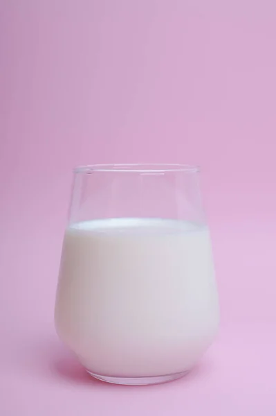 Vaso con leche sobre fondo rosa — Foto de Stock