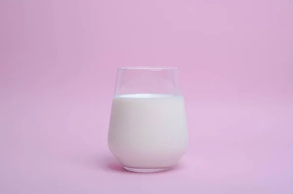 Vaso con leche sobre fondo rosa —  Fotos de Stock