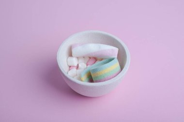 Pembe arkaplanda beyaz-pembe marşmelov ve reçel.