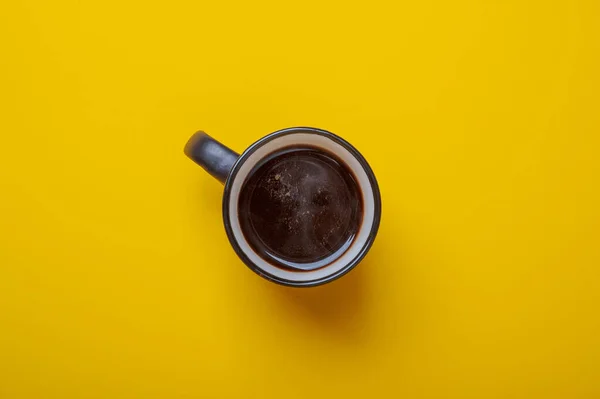 Black cup with coffee on yellow background top view — Stock Photo, Image