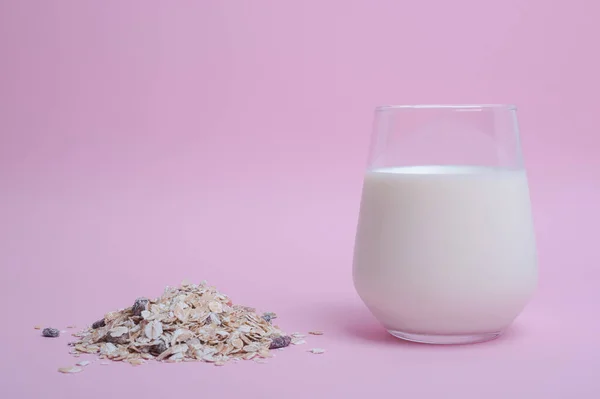 Saludable vaso de desayuno de leche al lado de muesli sobre fondo rosa — Foto de Stock