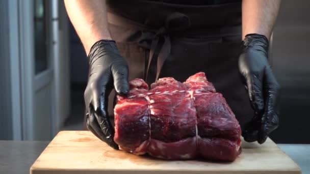 Un chef avec des gants met un morceau de viande crue sur une planche à découper — Video