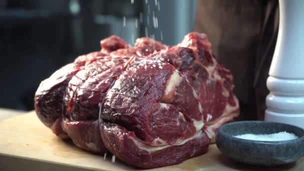 Handske kock strössel salt på en stor bit kött — Stockvideo