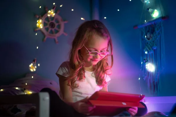  Gözlüklü kız gece tabletle oynuyor.