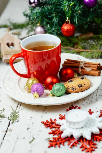 Kerstmis feest thee met kaneel, cookie en kerstballen met kerstboom achtergrond — Stockfoto
