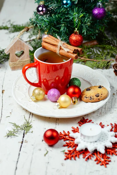 Kerstmis feest thee met kaneel, cookie en kerstballen met kerstboom achtergrond — Stockfoto