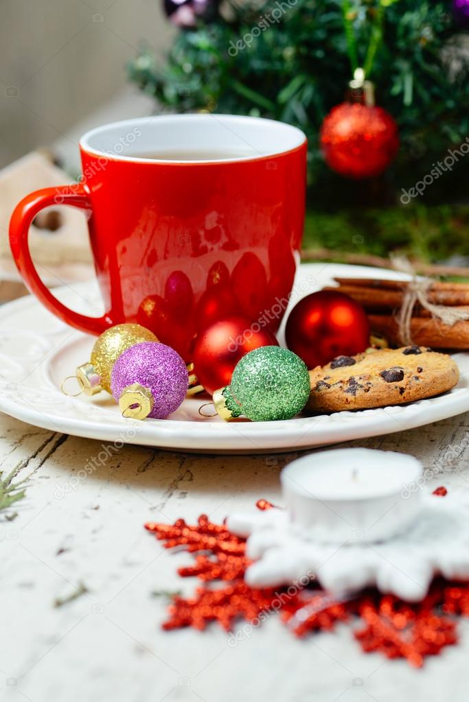 Christmas celebration tea time with cinnamon, cookie and baubles with Christmas tree background