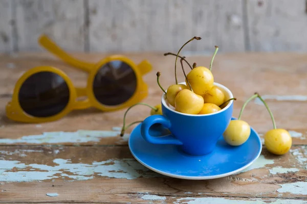 Blue tea cup full with yellow juicy cherries — Stock fotografie