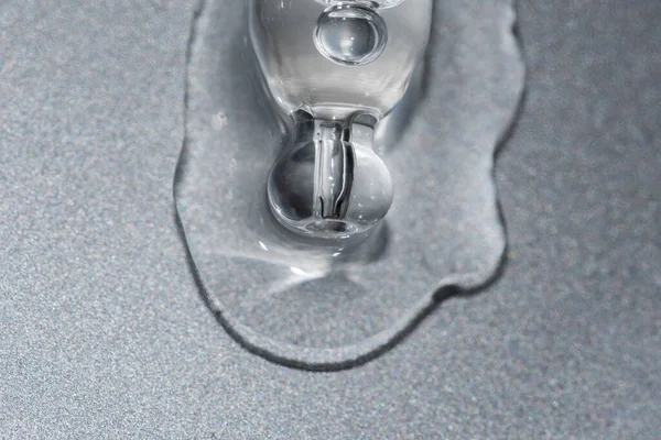 Макрос пипетки с жидкостью и капли на серебряном металлическом фоне — стоковое фото