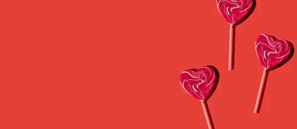 Lecca-lecca rosa a forma di cuore su sfondo rosso con banner spazio copia — Foto Stock