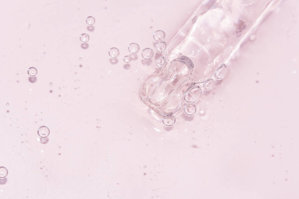 detail of a pipette with pouring serum and droplet with shadow