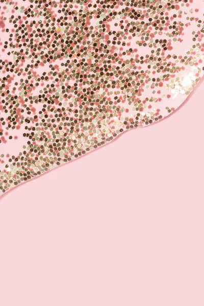 Transparent liquid with gold glitter pouring over a pastel pink background — Stock Photo, Image