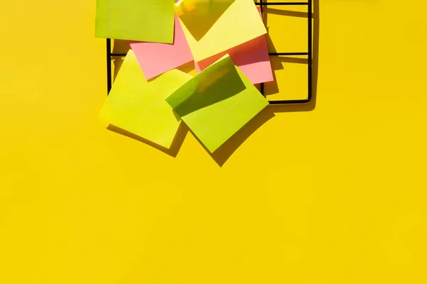 Grade de metal preto com notas coloridas em um fundo amarelo néon — Fotografia de Stock