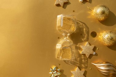 Şatafatlı altın bir Noel dairesi, çeşitli süsler ve altın bir zemin üzerinde kum saati.