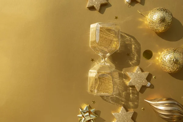 Luxe gouden Christmas platte lay van diverse ornamenten en zandloper op een gouden achtergrond — Stockfoto