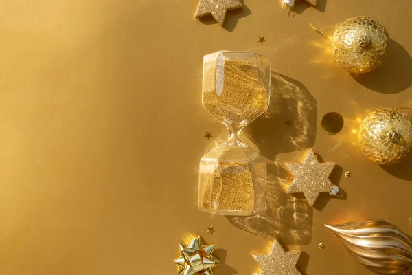 Şatafatlı altın bir Noel dairesi, çeşitli süsler ve altın bir zemin üzerinde kum saati.