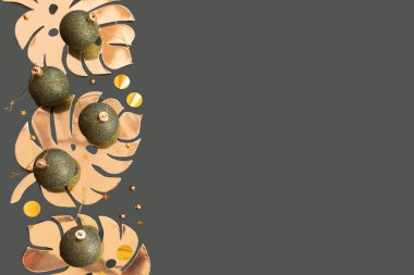 Koyu yeşil Noel mücevherleri, altın canavar yaprakları ve yeşil arkaplanda konfeti.