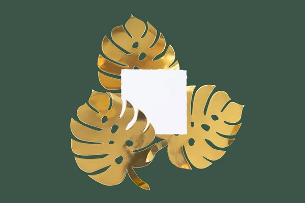 Papel dourado monstera folhas em uma garrafa escura fundo verde com cartão festivo pano de fundo de Natal — Fotografia de Stock