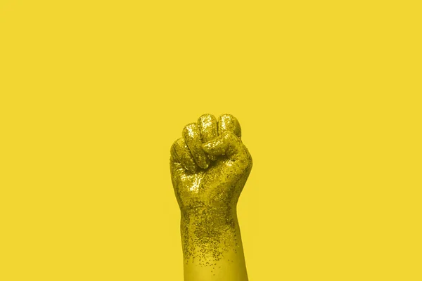 Feminism aktivism begrepp kvinna knytnäve täckt av guld glitter på gul bakgrund — Stockfoto
