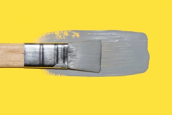 Pincel de pintura com tinta cinza final fresca em iluminar fundo amarelo — Fotografia de Stock