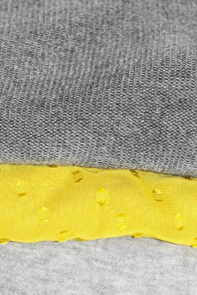 Detalhe close up de roupas empilhadas dobradas com cores da moda iluminando amarelo e cinza final — Fotografia de Stock