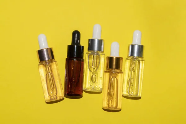 Juego de diferentes frascos con suero de belleza, ácido hialurónico y vitaminas sobre fondo amarillo — Foto de Stock