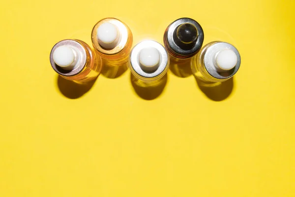 Набір різних пляшок з сироваткою краси, гіалуроновою кислотою та вітамінами на жовтому фоні — стокове фото