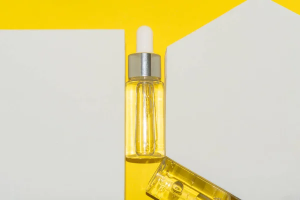 Botellas de suero de belleza entre formas geométricas blancas sobre un fondo amarillo — Foto de Stock