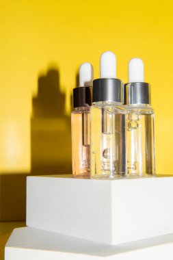 Güzellik serumu, hyaluronik asit ve sarı zemin üzerinde vitaminler olan farklı şişeler.