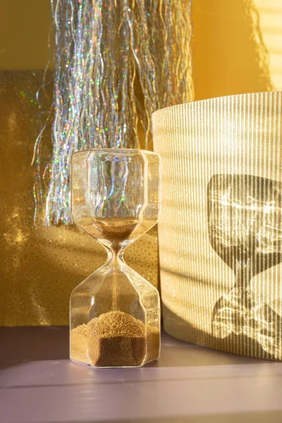 Zuur glas met gouden zand op een glanzende feestelijke gouden achtergrond — Stockfoto