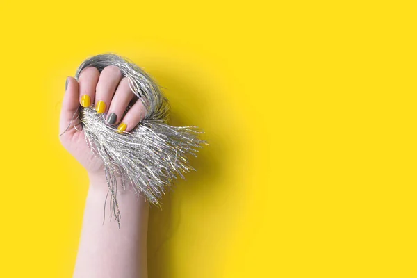 Részlet a nők kéz gazdaság ezüst tinsel rojtos manikűr — Stock Fotó
