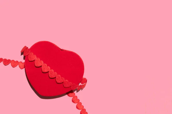 Caja de terciopelo rojo en forma de corazón sobre un fondo rosa — Foto de Stock