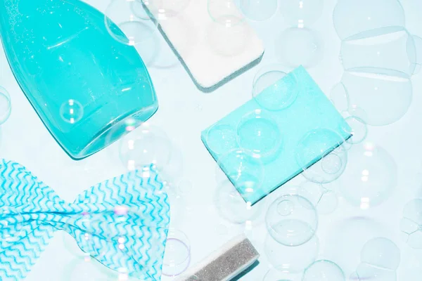 Esponjas azuis, toalhetes e spray de limpeza com bolhas em um fundo azul — Fotografia de Stock