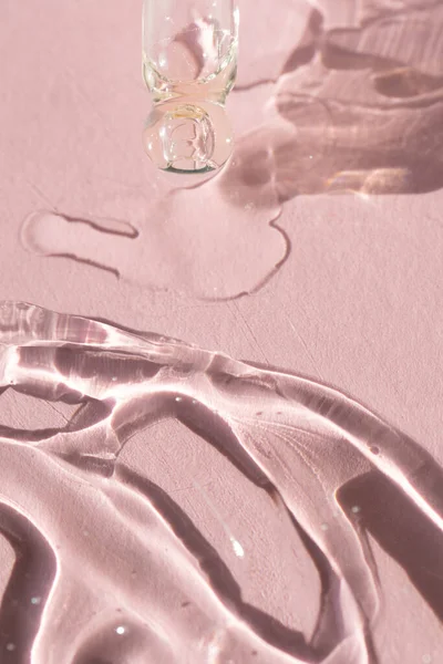 Zbliżenie kroplomierza pipety z wylaniem serum na twarz na różowym tle — Zdjęcie stockowe