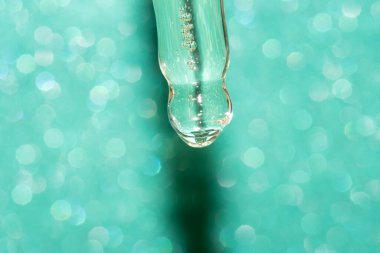 Turkuaz yeşil arkaplanda yüz serumu olan pipet damlatıcısının ayrıntıları