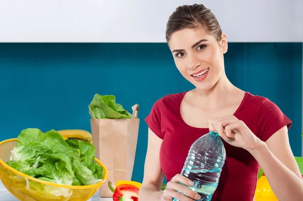 Woman in kitchen holding a bottle of water — Stock Photo, Image