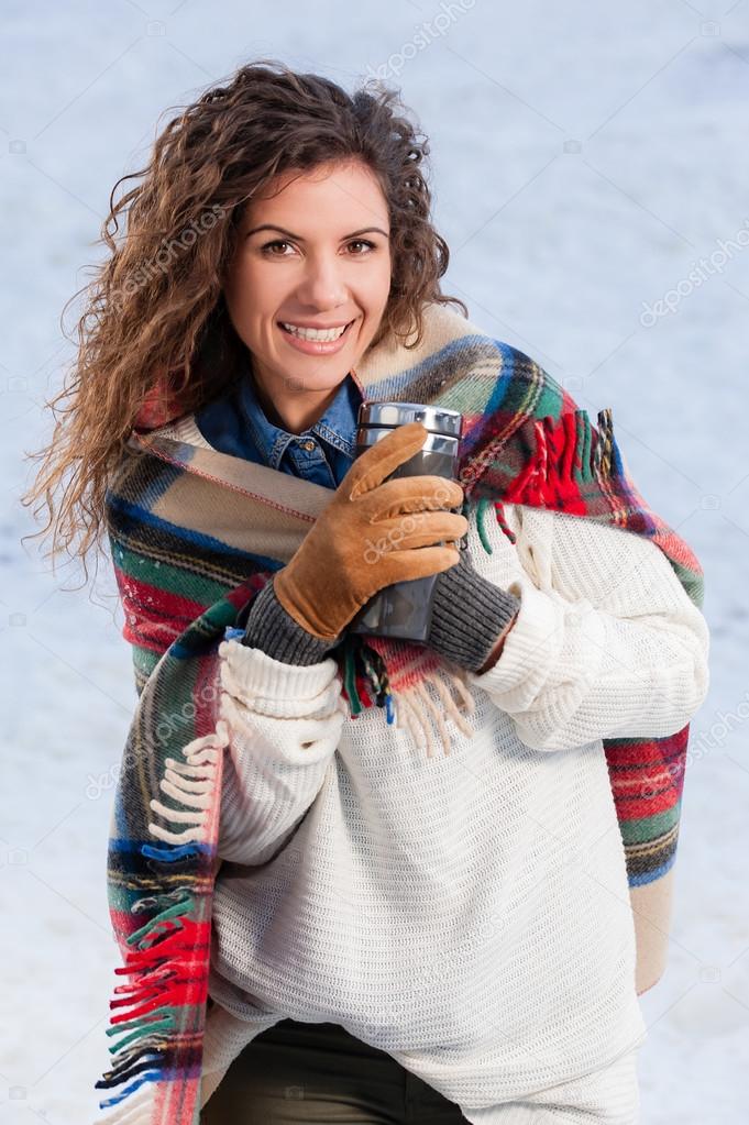 Drinking a hot drink from thermos in a cold day, outdoors.