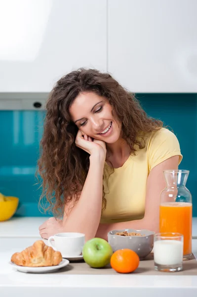 Pretty young girl sitting at the kitchen table, having breakfast. — Stock Photo, Image