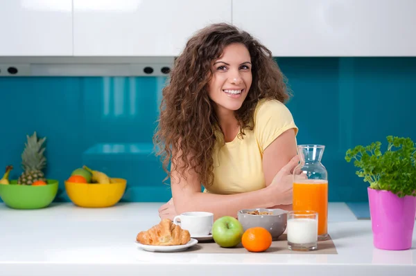 Pretty young girl sitting at the kitchen table, having breakfast. — Stock Photo, Image