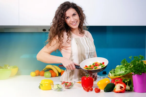 Young woman cooking healthy food holding a pan with vegetables is it — Stock Photo, Image