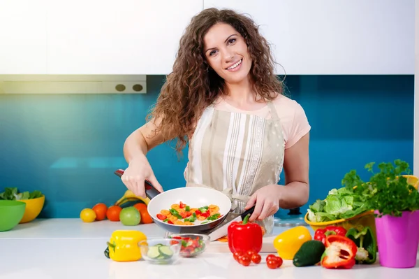 Junge Frau kocht gesundes Essen und hält eine Pfanne mit Gemüse in der Hand — Stockfoto