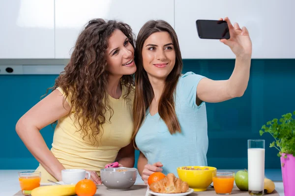 Two woman friends taking breakfast in the kitchen and having fun — Stock Photo, Image