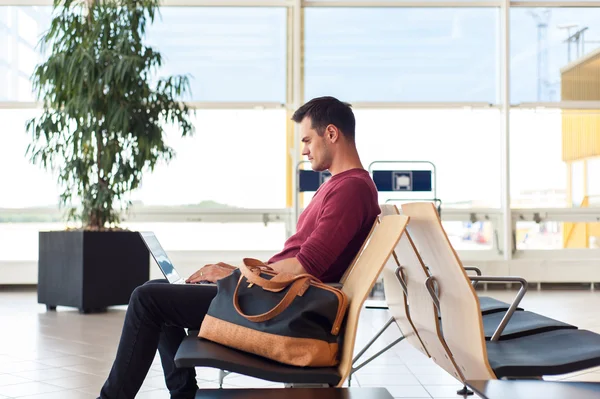 Uomo casuale nella sala dell'aeroporto che lavora sul computer portatile — Foto Stock