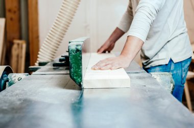 Carpenter working cutting some boards, he is wearing safety glasses and hearing protection